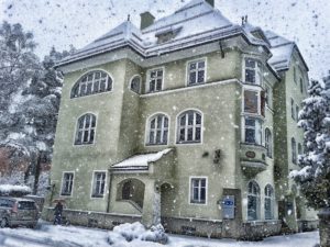 Big stone house with many windows and snow falling all around