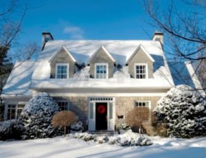Brick home with red front door and three dormers with snow on top and in the yard talking about replacement windows with Paul Henry's Windows